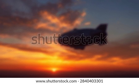 A blimp is silhouetted against a dramatic sunset sky filled with colorful clouds and the setting sun.