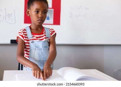 Blind african american elementary schoolgirl touching braille book while studying in classroom. unaltered, education, learning, studying, concentration, blindness, disability and school concept. - Powered by Shutterstock