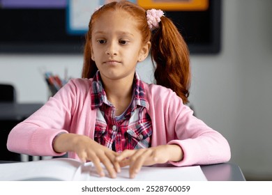 Blind, biracial schoolgirl sitting at desk reading braille in class. Education, childhood, elementary school, inclusivity and learning concept. - Powered by Shutterstock