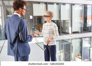 Blind businesswoman with long stick talking to African businessman - Powered by Shutterstock