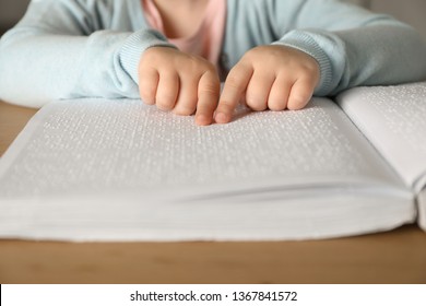 Blind Child Reading Book Written In Braille At Table, Closeup