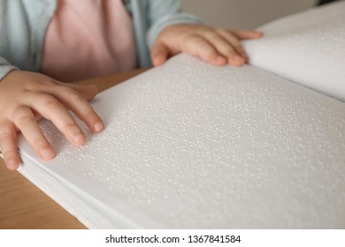 Blind Child Reading Book Written In Braille At Table, Closeup