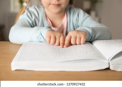 Blind child reading book written in Braille at table, closeup - Powered by Shutterstock