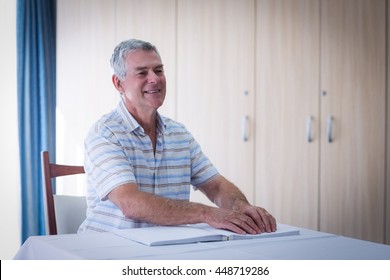 Blind man reading a braille book at home - Powered by Shutterstock