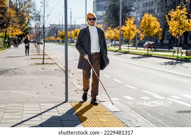 Blind man with a walking stick. Walks on tactile tiles for self-orientation while moving through the streets of the city