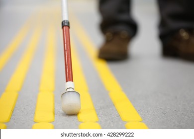 Blind pedestrian walking and detecting markings on tactile paving with textured ground surface indicators for blind and visually impaired. Blindness aid, visual impairment, independent life concept.