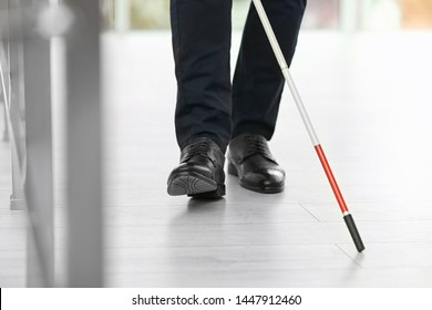 Blind person with long cane walking indoors, closeup