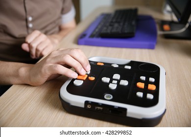 Blind person using audio book player for visually impaired, listening to audio book on his computer. Blindness aid, visual impairment, independent life concept. 