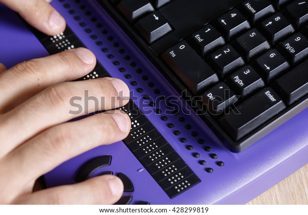 Blind person using computer with braille\
computer display and a computer keyboard. Blindness aid, visual\
impairment, independent life\
concept.\
