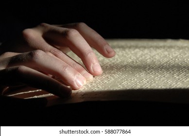 blind reading text in braille. close-up of human hands reading braille.