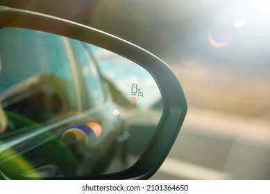 A blind spot monitoring sensor on the side mirror of a modern car