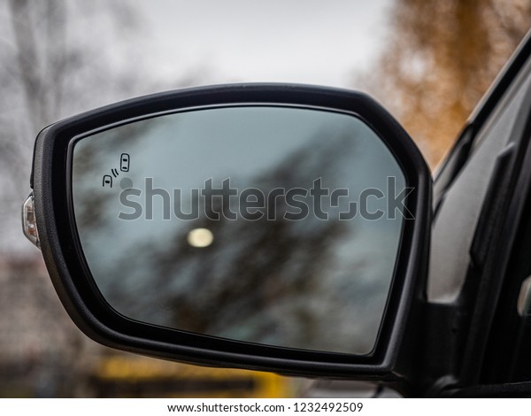 Blind Spot Monitoring system warning\
light/icon in side view mirror of a modern\
vehicle.