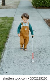 Blind Or Visually Impaired Child (Kid, Toddler, Boy) Walking On Sidewalk With White Cane; Cute And Happy