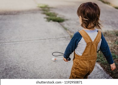 Blind Or Visually Impaired Child/Kid/Toddler/Preschooler/Boy Walking Through Neighborhood With Long White Cane; Back To Camera (Copy Space)