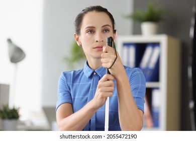 Blind woman with absent gaze looks into the distance and holds stick