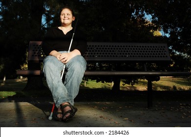 A blind woman enjoys the afternoon sun in a park