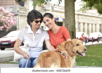 Blind woman and homecarer relaxing on bench