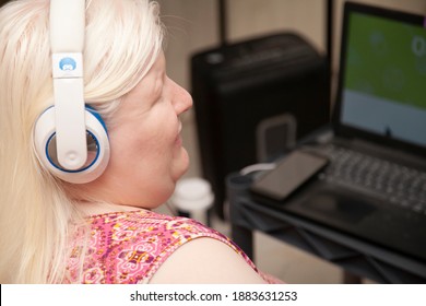 Blind Woman Listening To Headphones While On The Computer