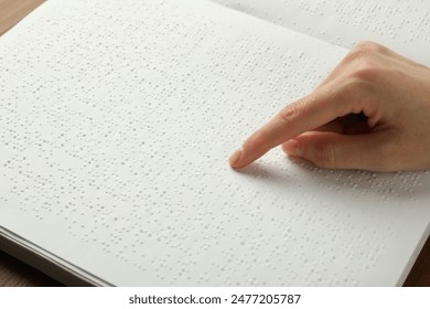 Blind woman reading book written in Braille at table, closeup - Powered by Shutterstock