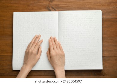 Blind woman reading book written in Braille at wooden table, top view - Powered by Shutterstock