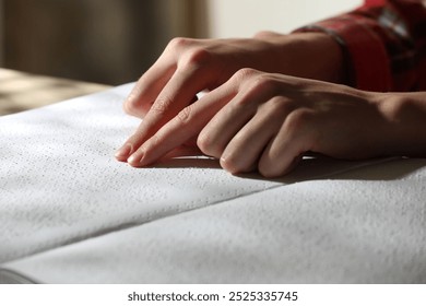 Blind woman reading book written in Braille at table, closeup - Powered by Shutterstock