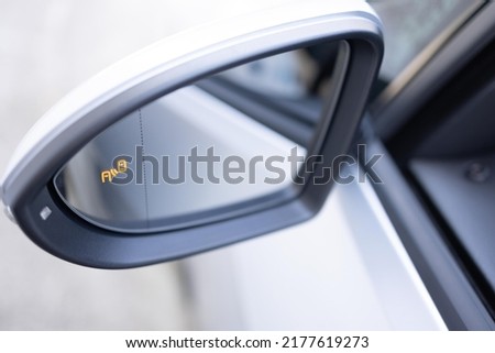 Blind zone monitoring sensor on the side mirror of a modern electric car. System blind spots of the car. Detail of side keeping assist system switch button.
