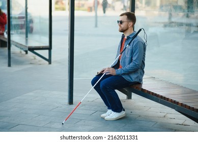 Blinded man waiting for bus at a bus station. - Shutterstock ID 2162011331