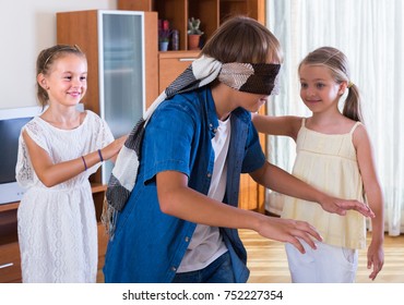 Blindfolded boy catching cute little sisters playing in Kagome at home