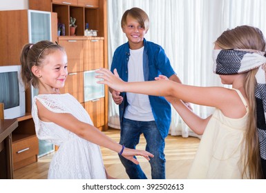 Blindfolded little girl catching cheerful kids playing in Kagome at home