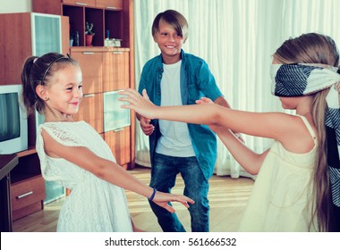 Blindfolded little girl catching cheerful kids playing in Kagome at home