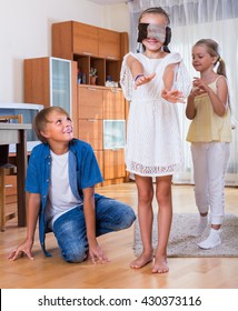 Blindfolded little girl catching other players in Kagome at home