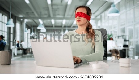 Blindfolded Man Struggles With Computer At Office Desk, Seeking Help.