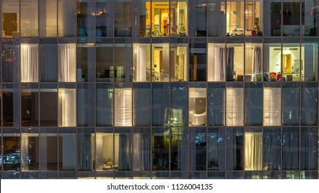 Blinking and flashing windows of the multi-storey building of glass and steel lighting inside and moving people within timelapse. Aerial view of modern residential skyscrapers in Dubai downtown. Pan - Shutterstock ID 1126004135