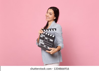 Blinking Pretty Young Woman In Striped Jacket Hold Classic Black Film Making Clapperboard Isolated On Pink Pastel Background In Studio. People Sincere Emotions, Lifestyle Concept. Mock Up Copy Space