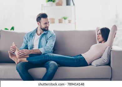 I bliss out and on cloud nine! Attentive caring loving handsome bearded husband is doing feet massage for her attractive tender lying on a sofa wife - Powered by Shutterstock