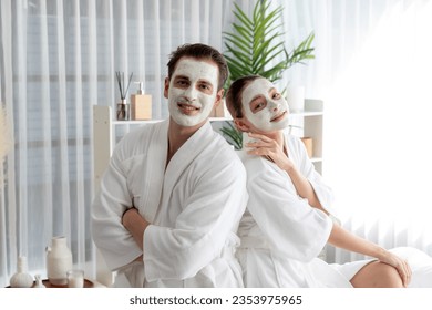 Blissful couple in bathrobe with facial cream mask enjoying serene ambiance of spa salon resort or hotel during holiday. Pampering face spa and skincare treatment with essence relaxation. Quiescent - Powered by Shutterstock