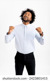 Blissful happy african-american male office employee raising clenched fists up in sign of victory, happy black man in formal wear celebrating success or good deal, looking up and thanking god