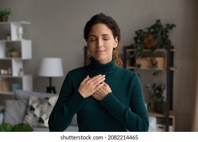 Blissful minute. Peaceful young latin female stand alone keep eyes closed put hands on heart pray thank god for kind wonderful things in life. Sincere lady feel grateful to fate for every good moment - Shutterstock ID 2082214465