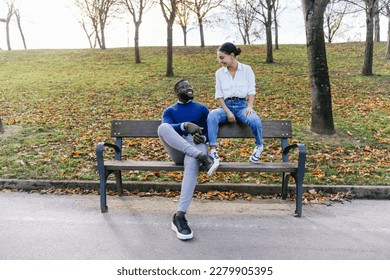 Blissful Multiracial Couple Embracing in Park Bench Amidst Falling Leaves and Sunset Glow - Powered by Shutterstock
