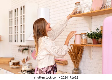 Blissful pretty blonde woman puts things and order and organizing stuff at her cozy kitchen, home style concept.  - Shutterstock ID 2024491682