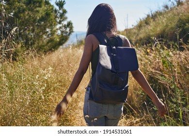 A blissful young lady walking through the wild outdoors and running her fingers through the long dry bushes - Shutterstock ID 1914531061