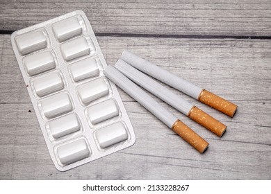 A Blister Pack With Nicotine Gum And Three Cigarettes On A Wooden Background As A Symbol Of Smoking Cessation