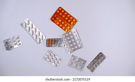 Blister Pack With Pills And Capsules Thrown On White Background. Pills Fall On Table. Medicines For Treatment And Prevention Of Diseases. Vitamins, Supplements, Antibiotics, Antivirals, Sedatives