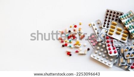 Blisters with various pills and capsules on a white background with copy space. Medicine, pharmaceuticals, treatment and prevention of diseases.