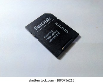 Blitar , Indonesia - January 10th 2021 - Sandisk brand micro sd adapter is black on a white wooden table