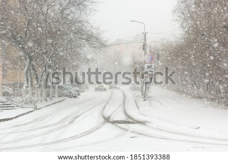 Blizzard, mist and snowfall in city, cars on sleet road, poor visibility, winter bad weather