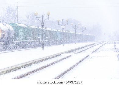 Blizzard On Railway, Freight Train In Snow And Traffic Lights Behind