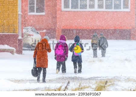 Blizzard in an urban environment, people, children walk home from school during snowfall in winter.

