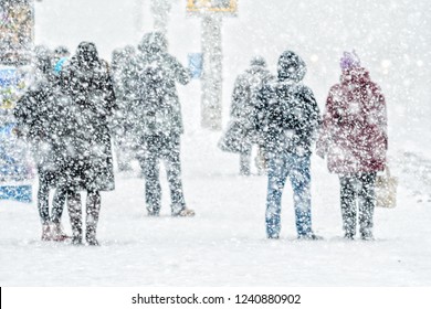 Blizzard in an urban environment. People on bus stop in snowfall. Abstract blurry winter weather background