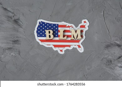 BLM Word On A Gray Background With American Flag. Fight Against Racism Concept.